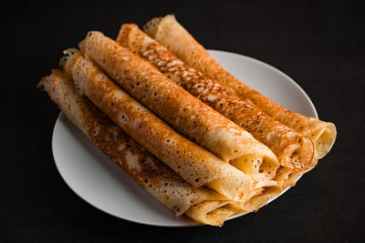 Tasty crepes on a plate on a black background. traditional russian food. place for your text.