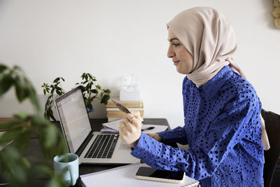 Woman in headscarf paying bills online at home