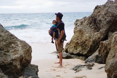 Rear view of man standing on rock at beach