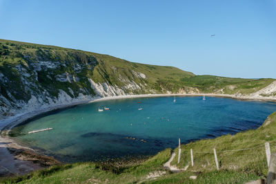 Scenic view of sea and mountains against clear blue sky