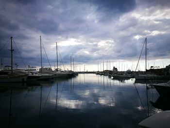 Sailboats moored in harbor against sky