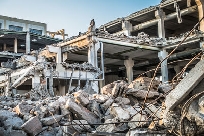 Abandoned building by construction site against sky