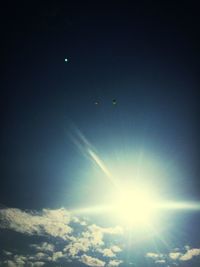 Low angle view of sun shining through clouds