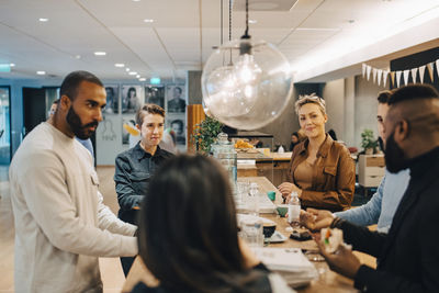 Male and female professionals discussing during meeting at cafeteria in office