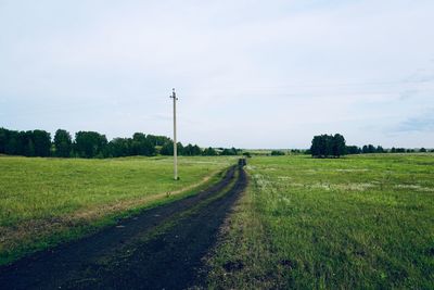 Scenic view of road amidst field against sky