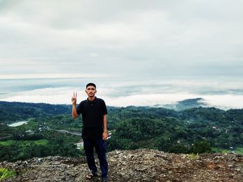 Young man standing on mountain against sky