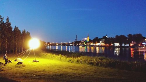 River by illuminated city against clear sky at night