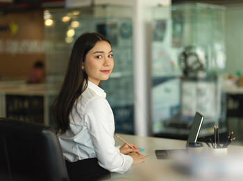 Portrait of businesswoman holding pencil at office