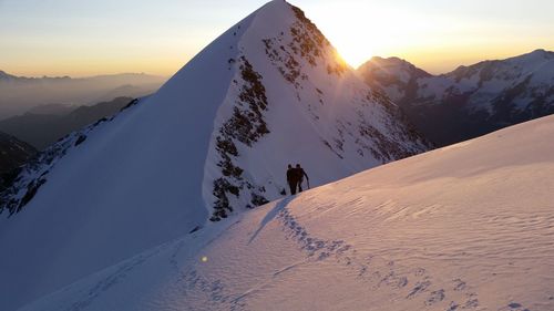 Couple on snowcapped mountain during sunrise