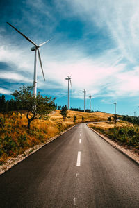 Wind turbines on road against sky