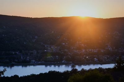 Scenic view of river by silhouette mountains against clear sky