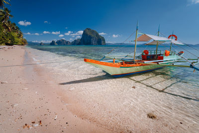 Boat moored on beach against sky