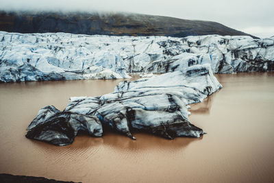 Frozen lake against snowcapped mountains