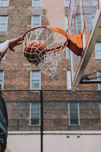 Midsection of man playing basketball against building