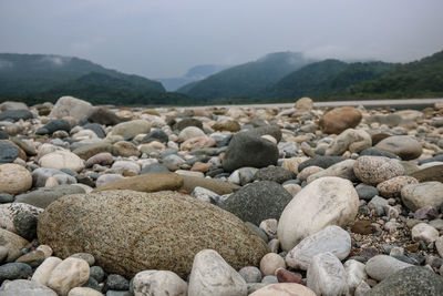 Close-up of pebbles on beach against sky