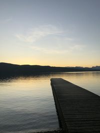 Pier over lake against sky during sunset