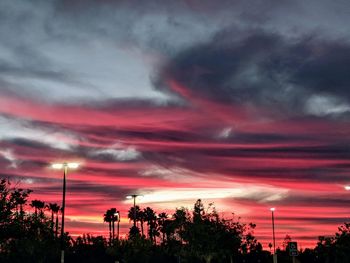 Low angle view of silhouette trees against dramatic sky