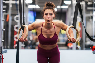 Portrait of young woman exercising on gymnastics rings