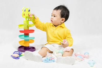 Boy playing with toy blocks against white background
