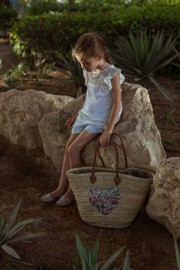 Full length of cute girl sitting on rock