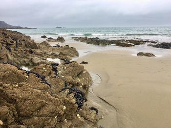 Scenic view of rocks on beach against sky