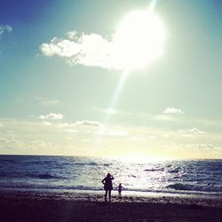 Silhouette people standing on beach against sky