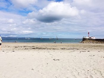 Scenic view of beach against cloudy sky