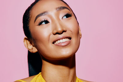 Close-up of young woman against pink background