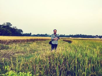 Portrait of man standing on field against sky