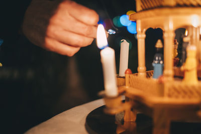 Cropped hand igniting candle in darkroom