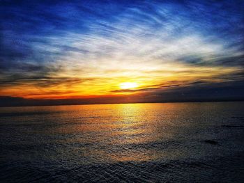 Scenic view of sea against dramatic sky during sunset