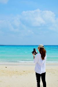 Woman standing at beach against sky