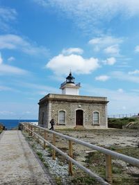 Man walking by lighthouse against sky at costa brava