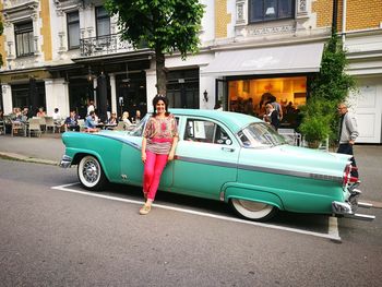 Portrait of mature woman standing by vintage car on street in city