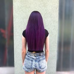 Rear view of woman standing against wall in city