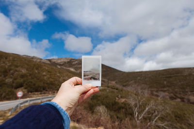 Close-up of person holding camera on mountain