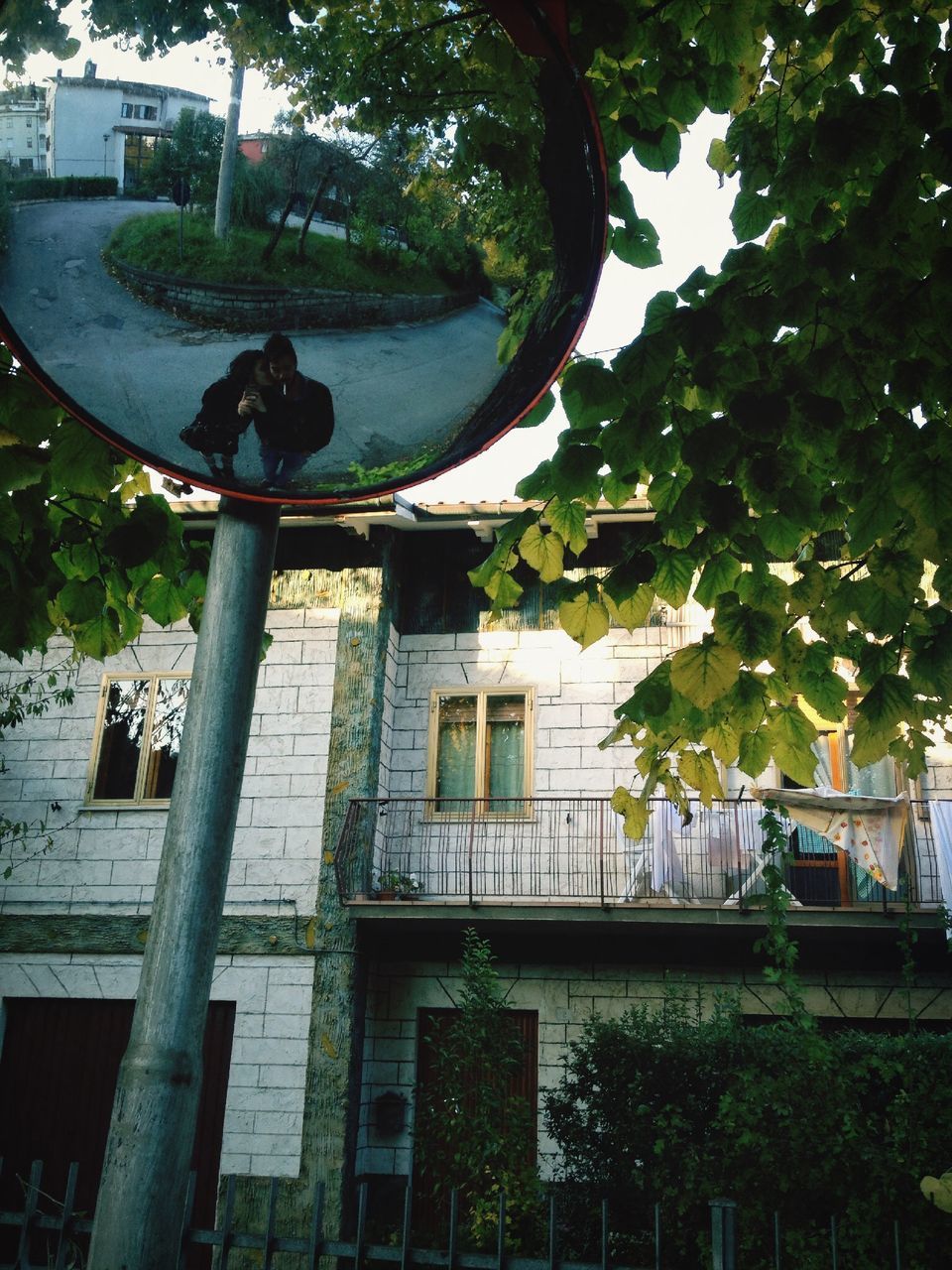 tree, water, building exterior, built structure, architecture, park - man made space, incidental people, railing, growth, outdoors, day, nature, fountain, sunlight, city, chair, street light, reflection, branch, bench