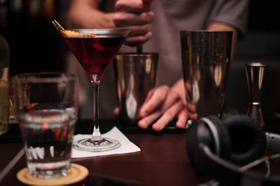 Midsection of man having wine glasses on table