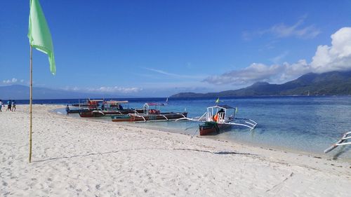 Outrigger boats at beach against sky