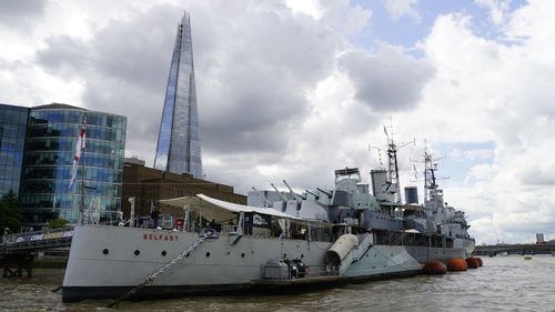 Ship moored in sea against cloudy sky