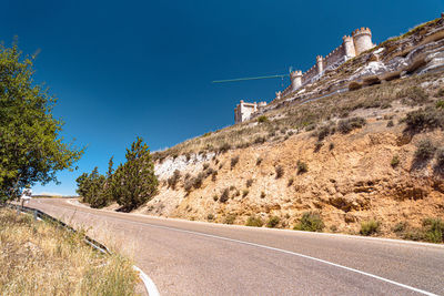 Road amidst trees against clear blue sky