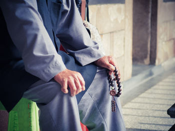 Midsection of man holding umbrella while standing in city