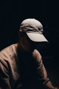 Midsection of man wearing hat against black background