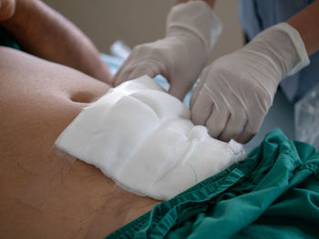 Midsection of nurse putting cotton stomach of patient at hospital