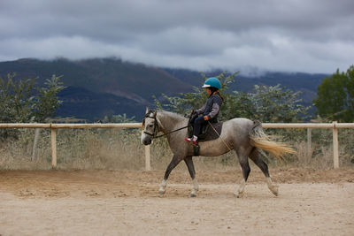 5-year-old girl riding on a horse, in a hipico club. infalltil sport concept.