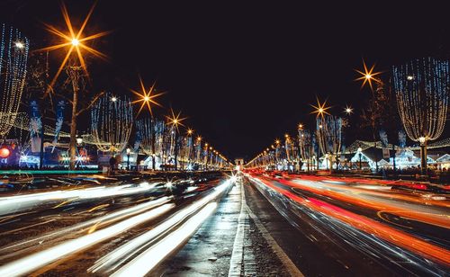 Light trails on street against sky at night