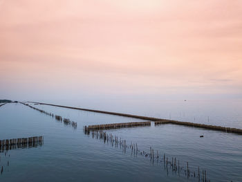 Pier on sea against sky during sunset