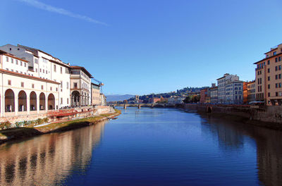 River by buildings against clear blue sky in city