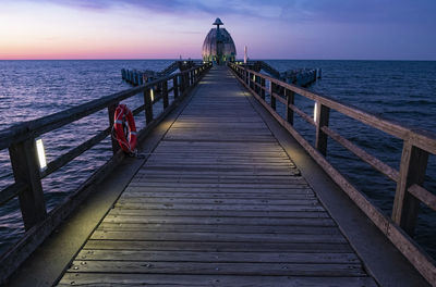 Pier over sea against sky during sunset
