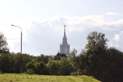 View of trees and building against cloudy sky